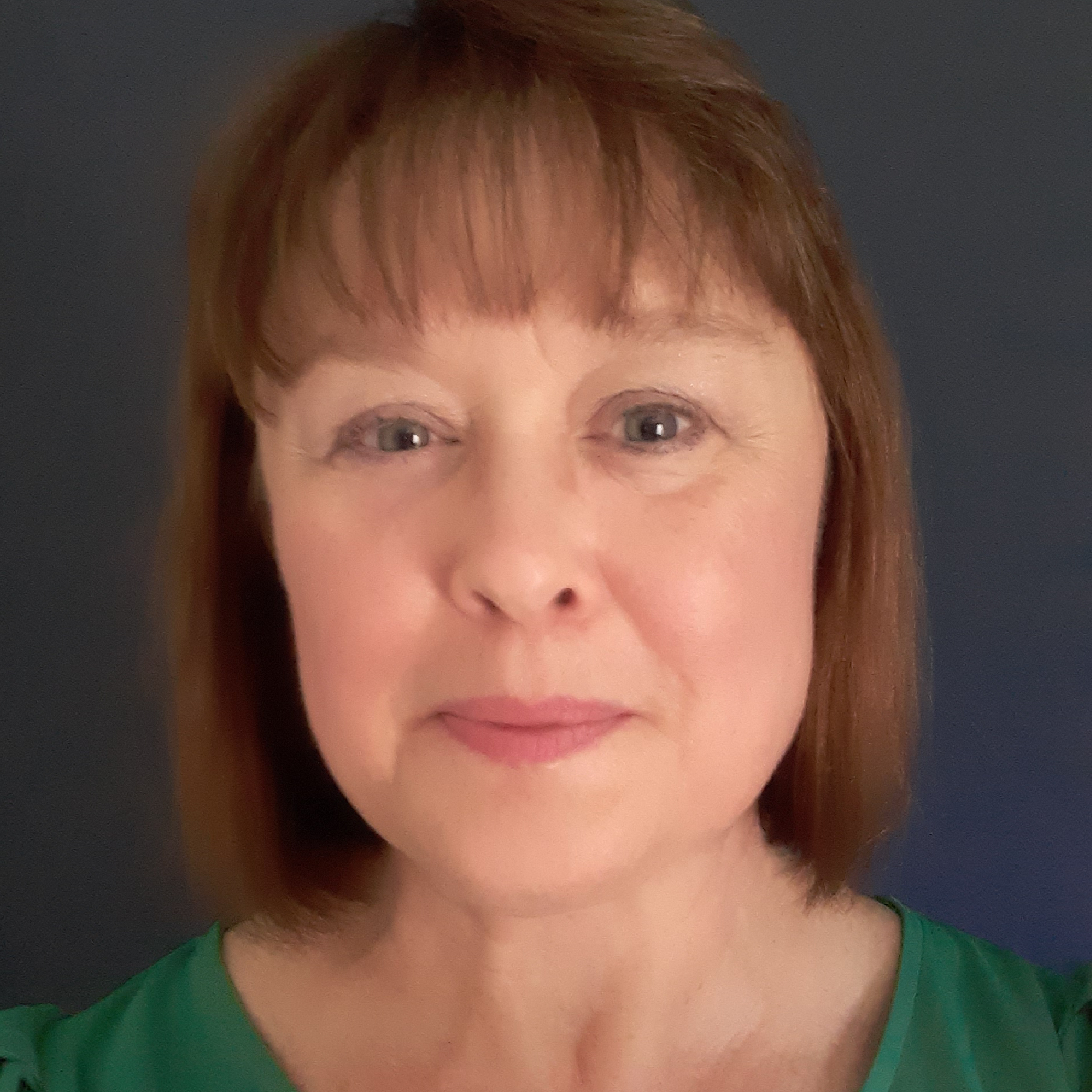 Dawn Knorr. A woman with light skin and straight auburn hair smiles softly against a dark background.