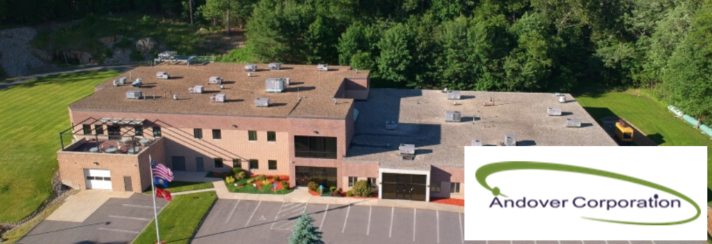 Aerial view of a building with trees behind it; Andover Corporation logo is overlaid in the bottom right. Apply Now for Optical Manufacturing Production Assistant Apprenticeship.